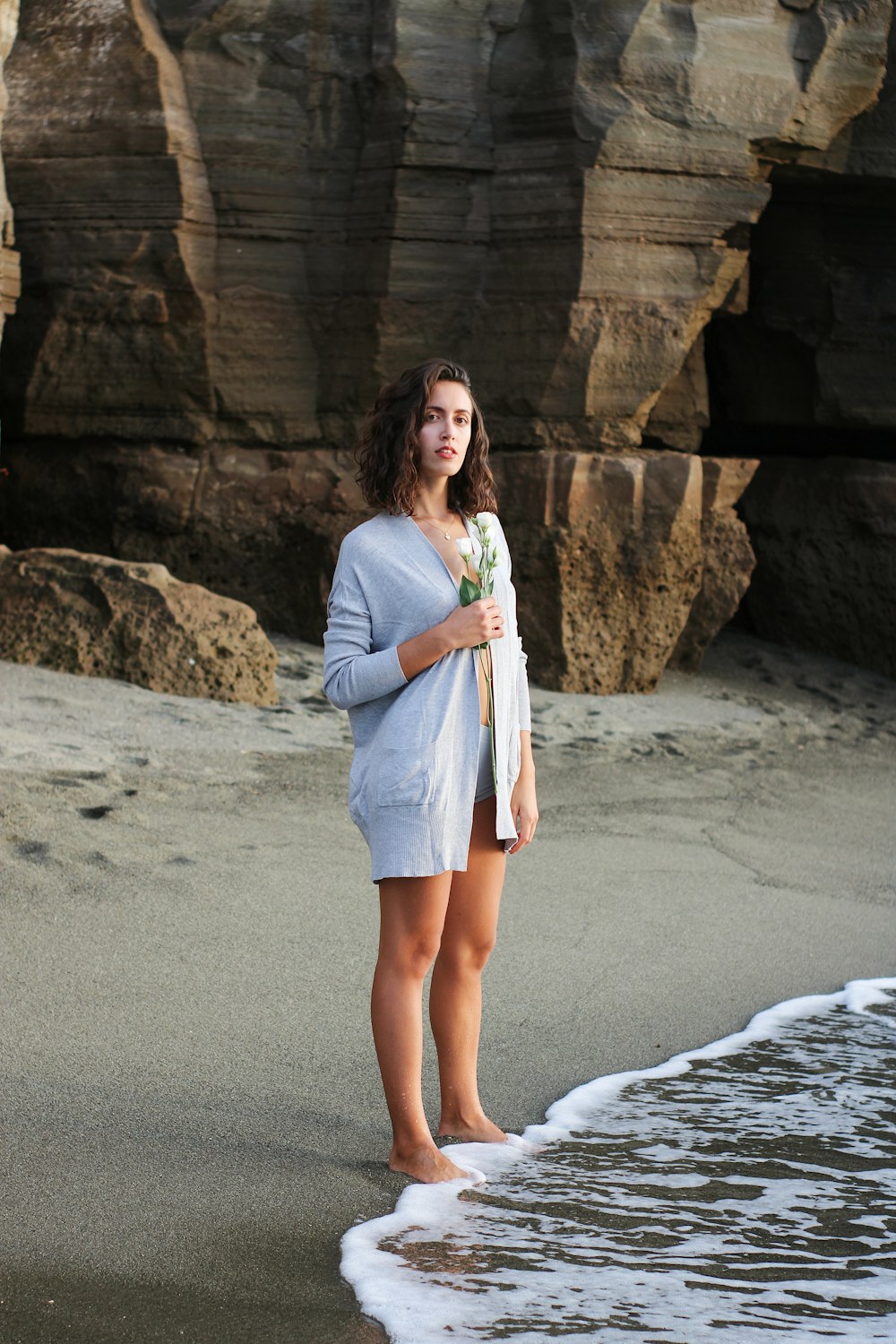 a woman standing on a beach next to the ocean