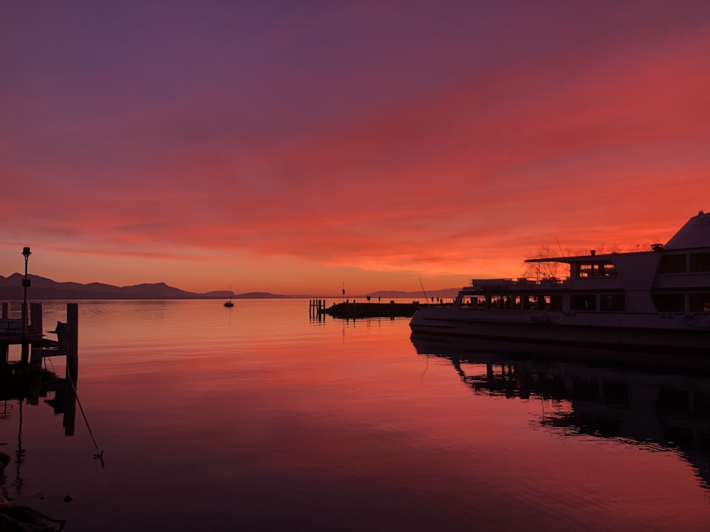 a sunset over a body of water with a boat in the distance