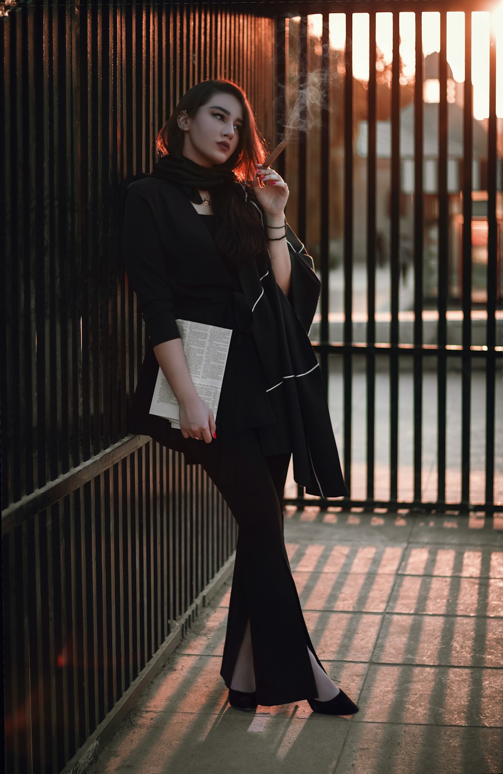 a woman in a black outfit smoking a cigarette