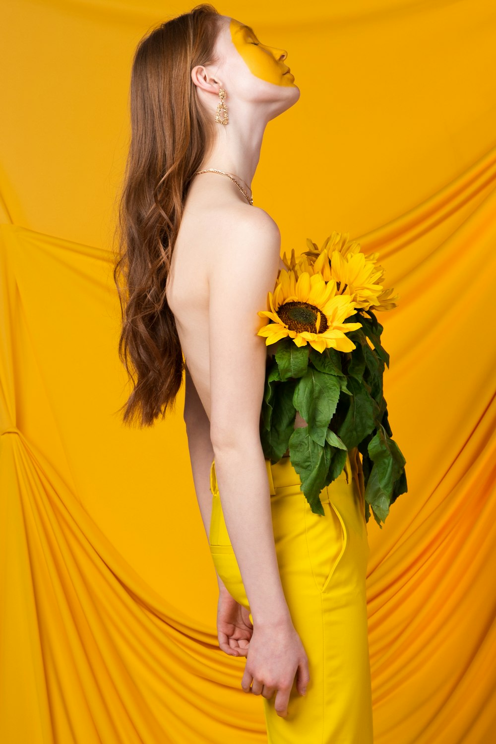 a woman in a yellow dress holding a sunflower