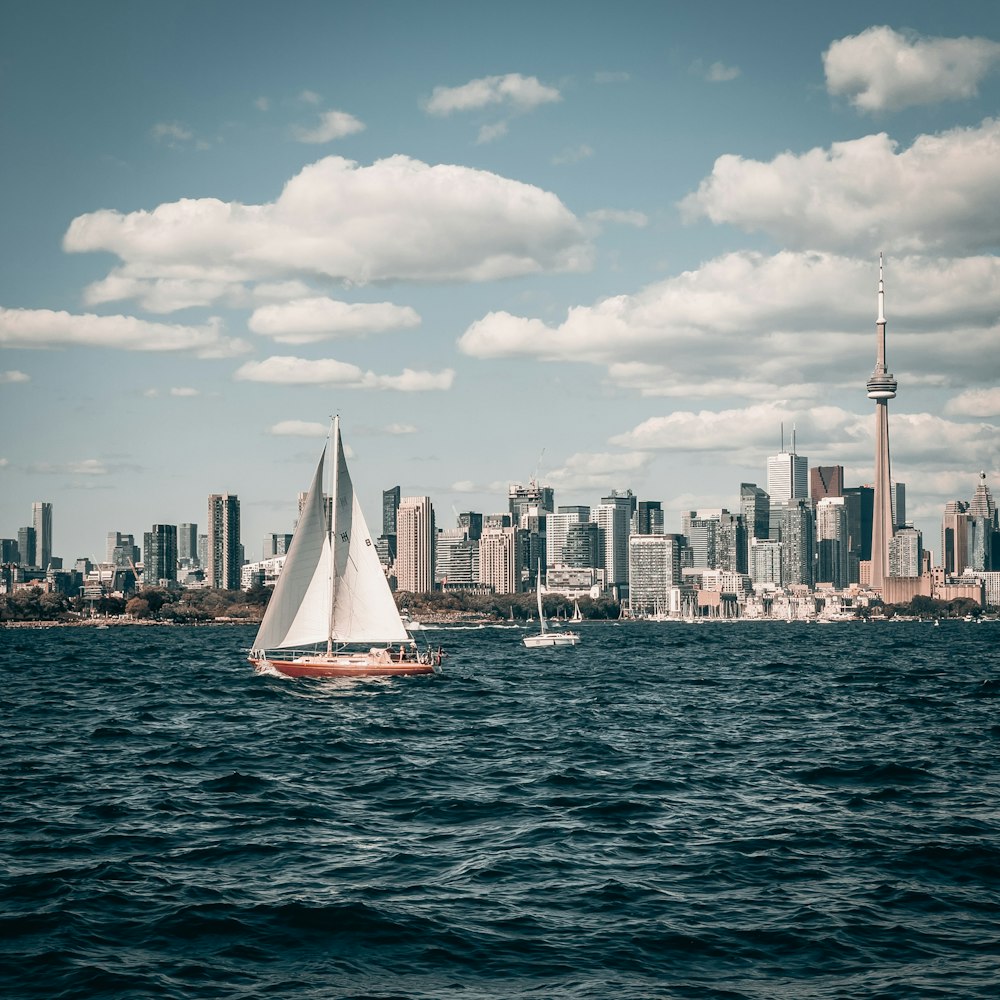 a sailboat in a body of water with a city in the background