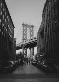 a black and white photo of people walking under a bridge
