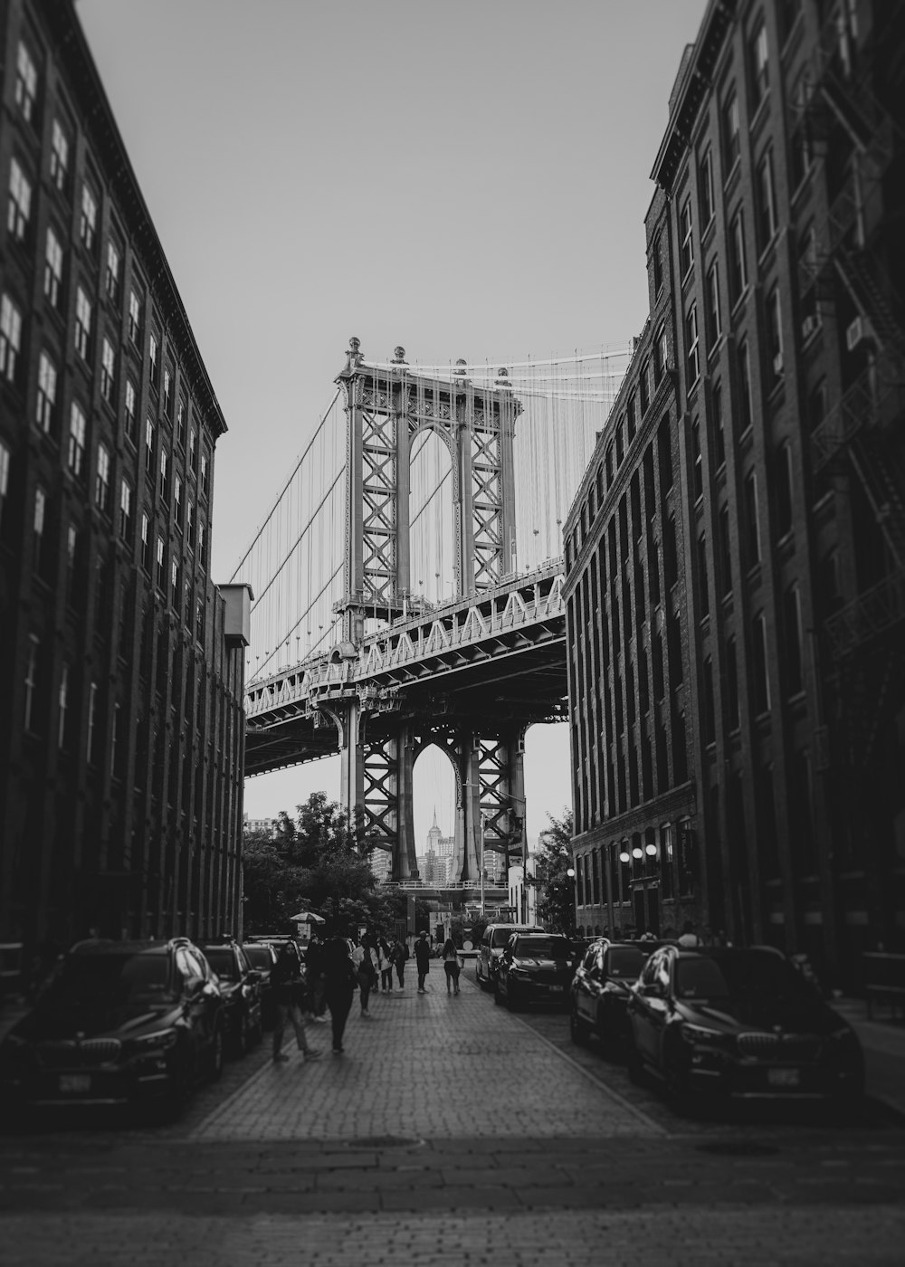 a black and white photo of people walking under a bridge