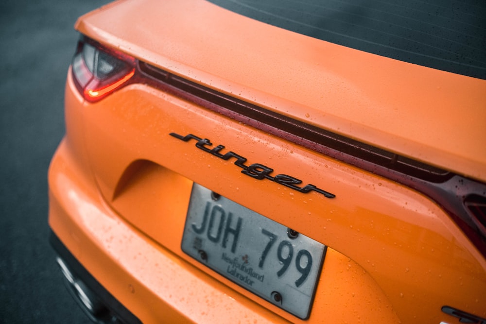 a close up of the rear end of an orange sports car