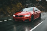 Red sports car gleaming on a mountain highway curve.