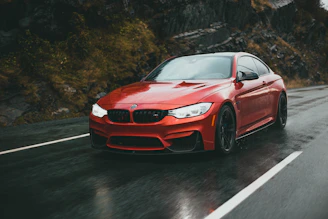 A sleek, red mach1 performance car hugging a winding mountain road at sunset.