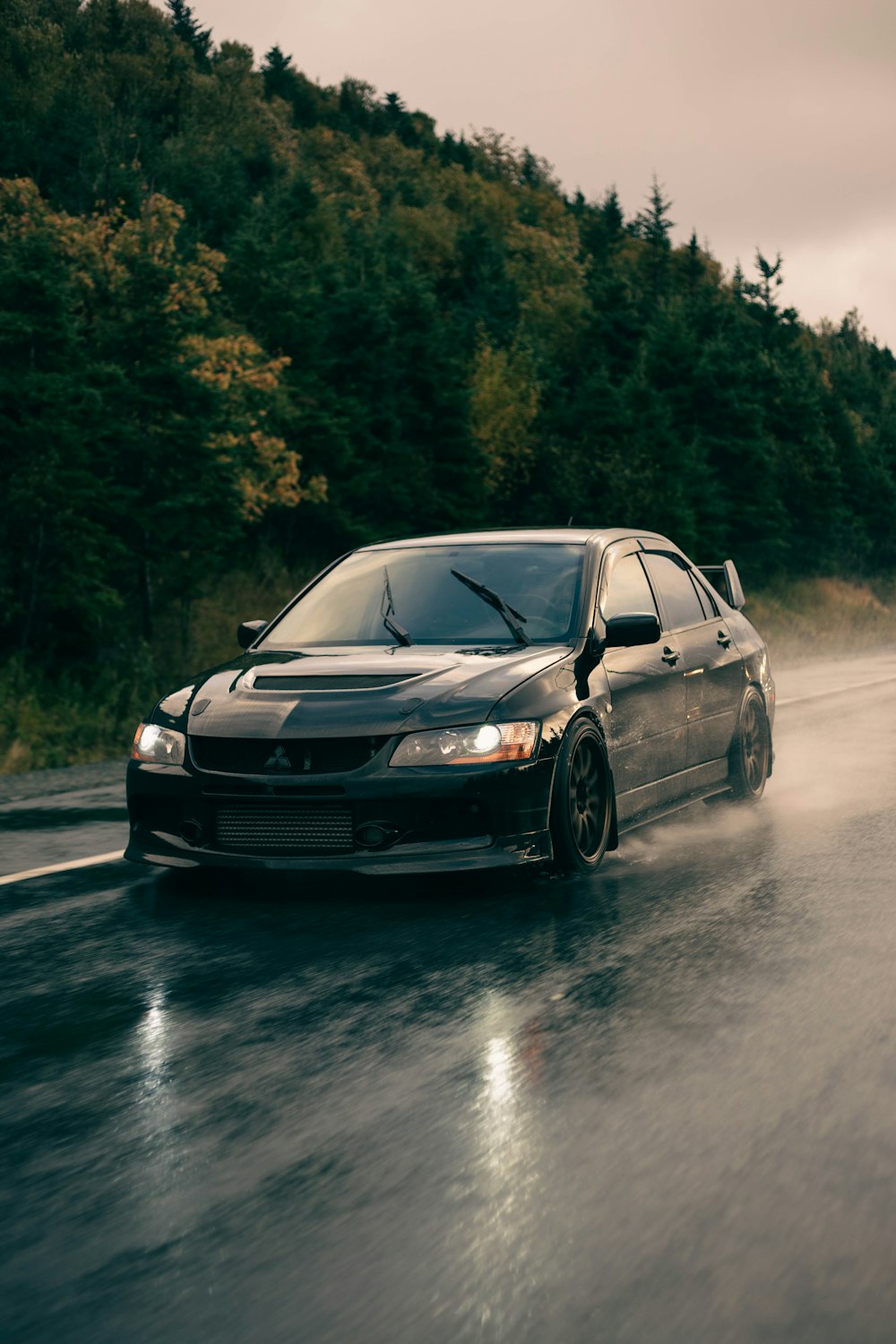 a car driving down a wet road with trees in the background