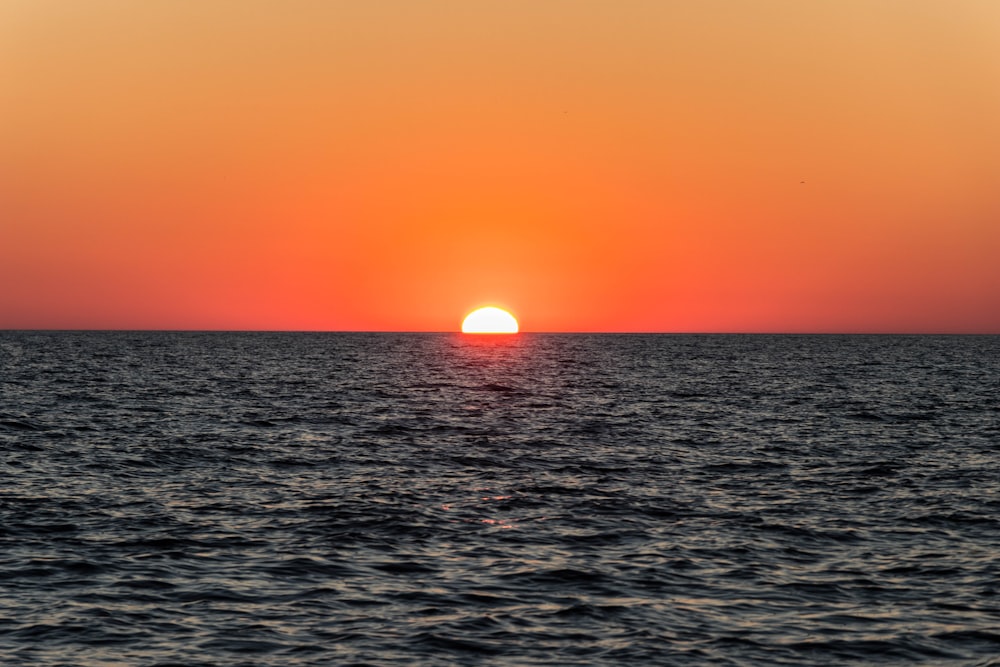 a large body of water with a sunset in the background