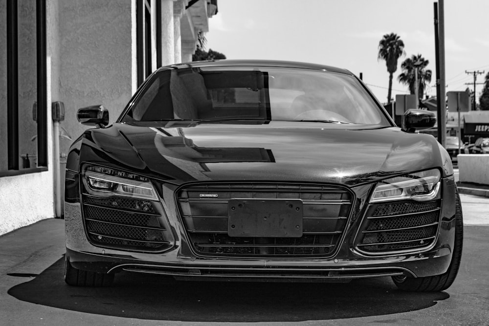 a black and white photo of a car parked in front of a building