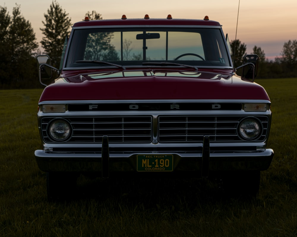 a red truck parked on top of a lush green field