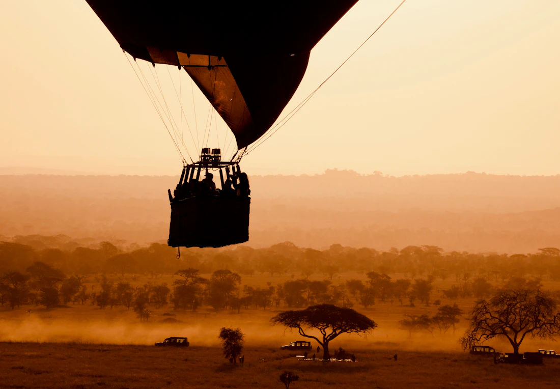 A hot-air balloon drifting low over the plains at sunrise on safari in East Africa