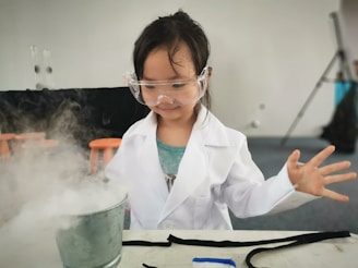 a little girl wearing a white lab coat and goggles