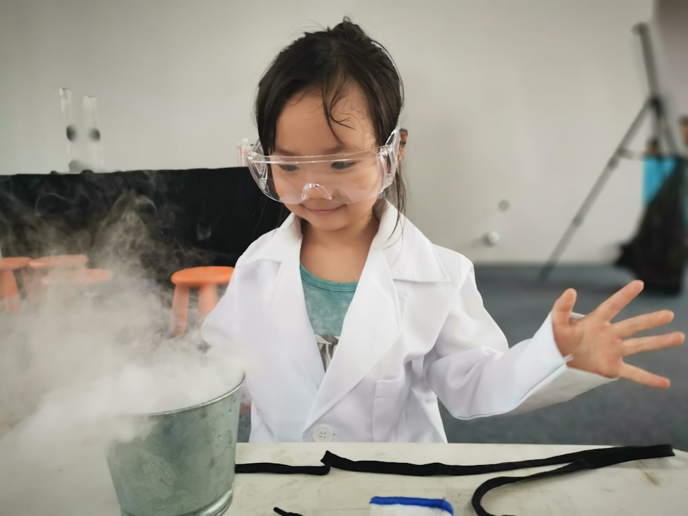 Una niña pequeña con una bata blanca de laboratorio y gafas