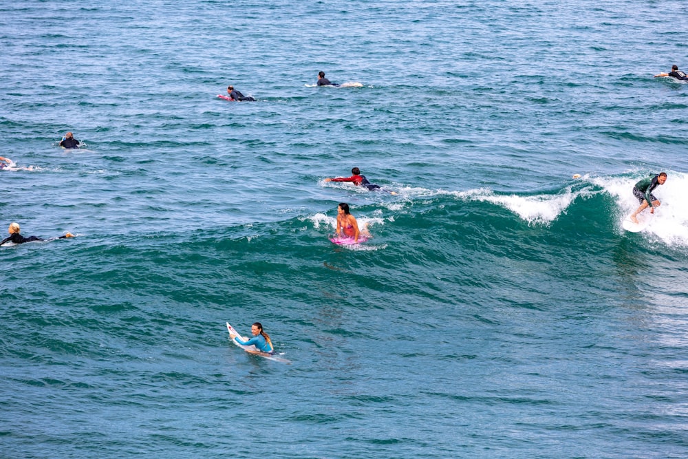 a group of people riding surfboards on top of a wave