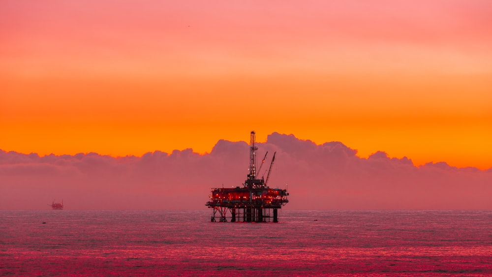 uma plataforma de petróleo no meio do oceano ao pôr do sol