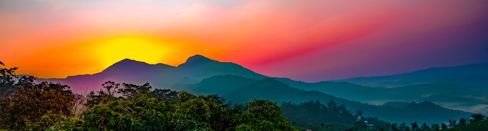 the sun is setting over a mountain range