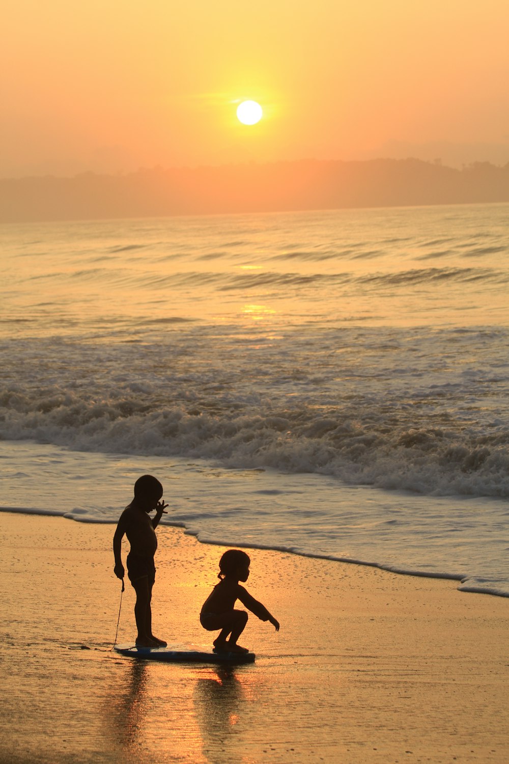 a couple of kids standing on top of a beach