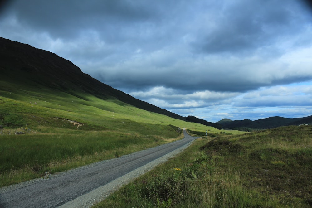 a road in the middle of a lush green valley