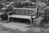 a wooden bench sitting next to a stone wall