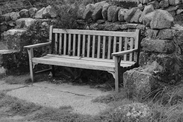 a wooden bench sitting next to a stone wall