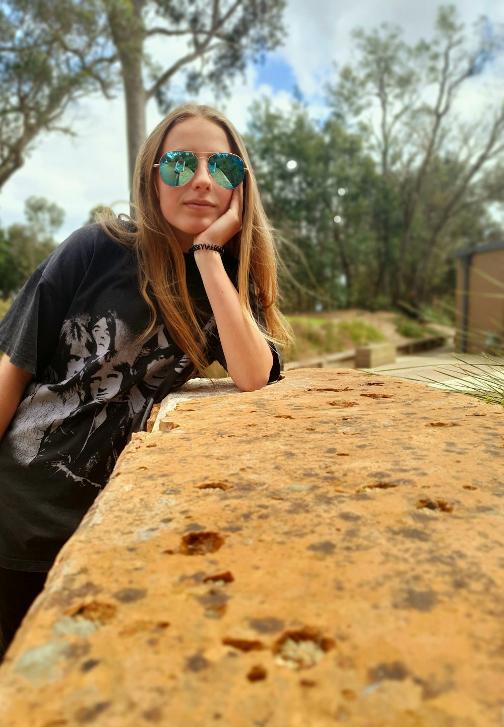 a girl wearing sunglasses leaning on a wall