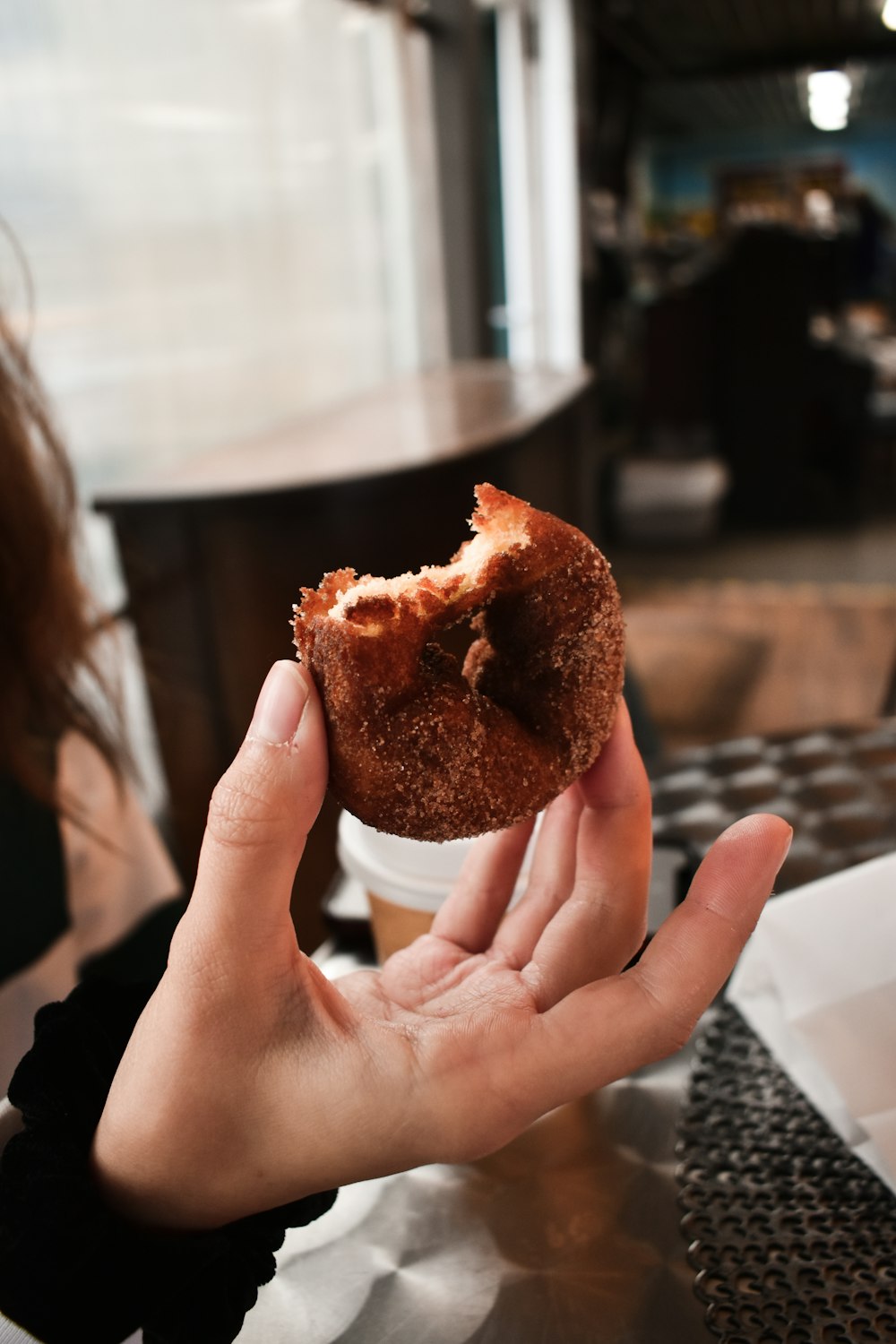 una persona sosteniendo una rosquilla a medio comer en la mano