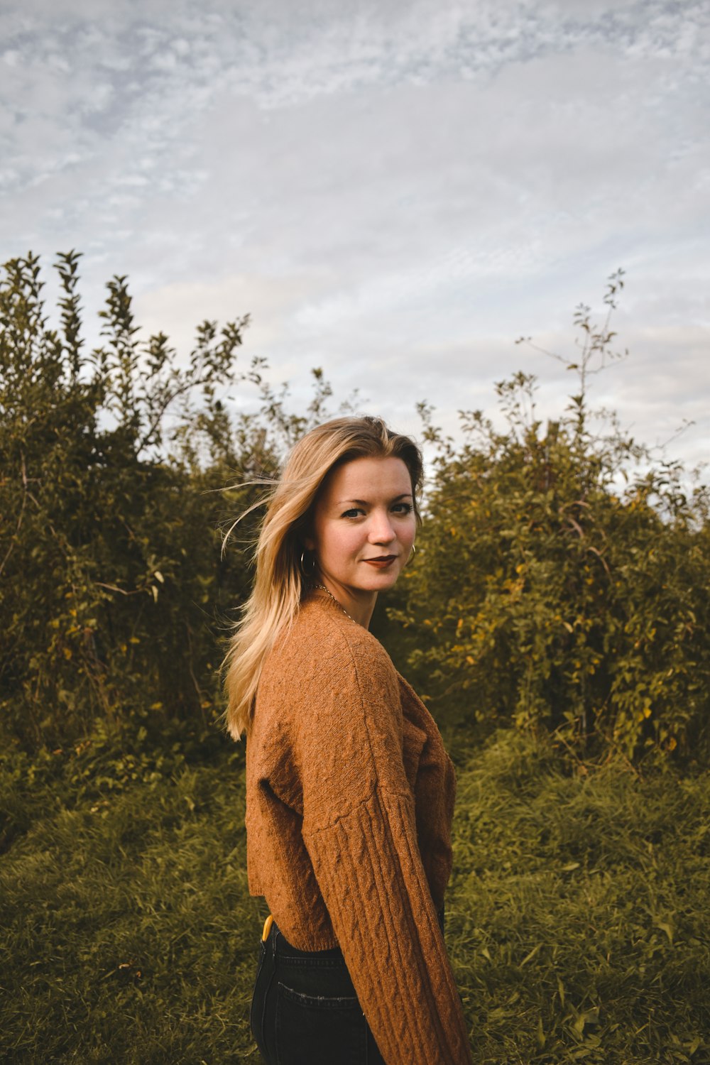 a woman standing in a field of tall grass