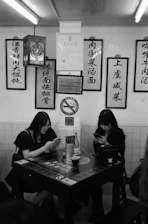 A happy couple using a smartphone to reserve a table and pay online at an Asian restaurant.