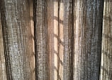 Vertical, textured curtains with light streaming through, creating a pattern of shadows.