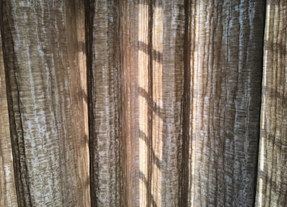 Vertical, textured curtains with light streaming through, creating a pattern of shadows.