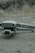 A drone labeled 'Mavic 2' with a Hasselblad camera rests on a textured asphalt surface. The background features blurred grass and rocks.