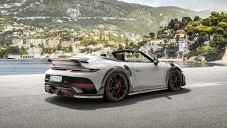 a white sports car parked in front of a lake
