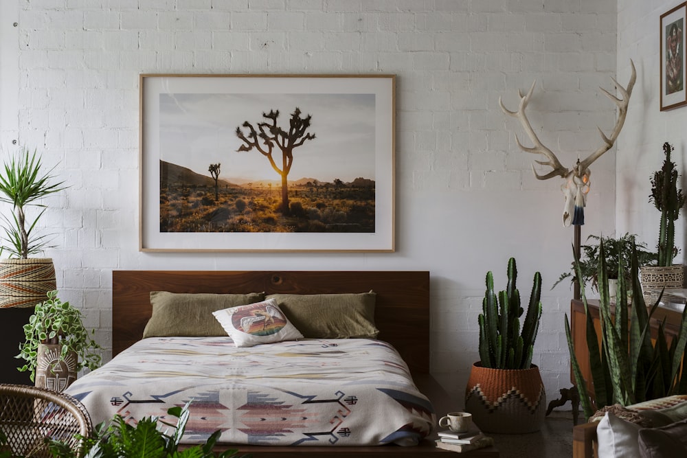 a bedroom with a bed, plants, and a picture on the wall