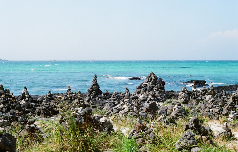 a group of rocks sitting on top of a beach next to the ocean