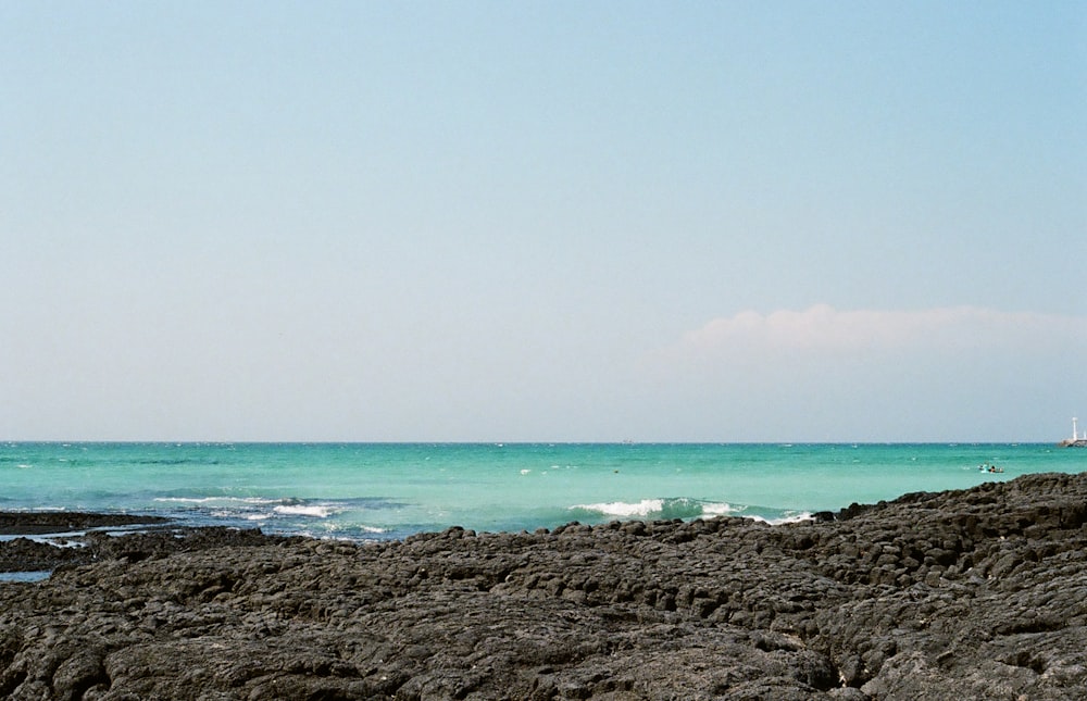 a person standing on a rocky beach next to the ocean