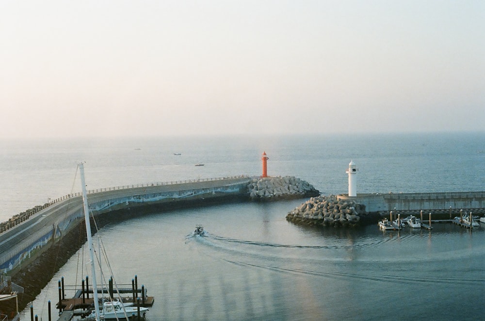 a boat traveling down a body of water next to a light house