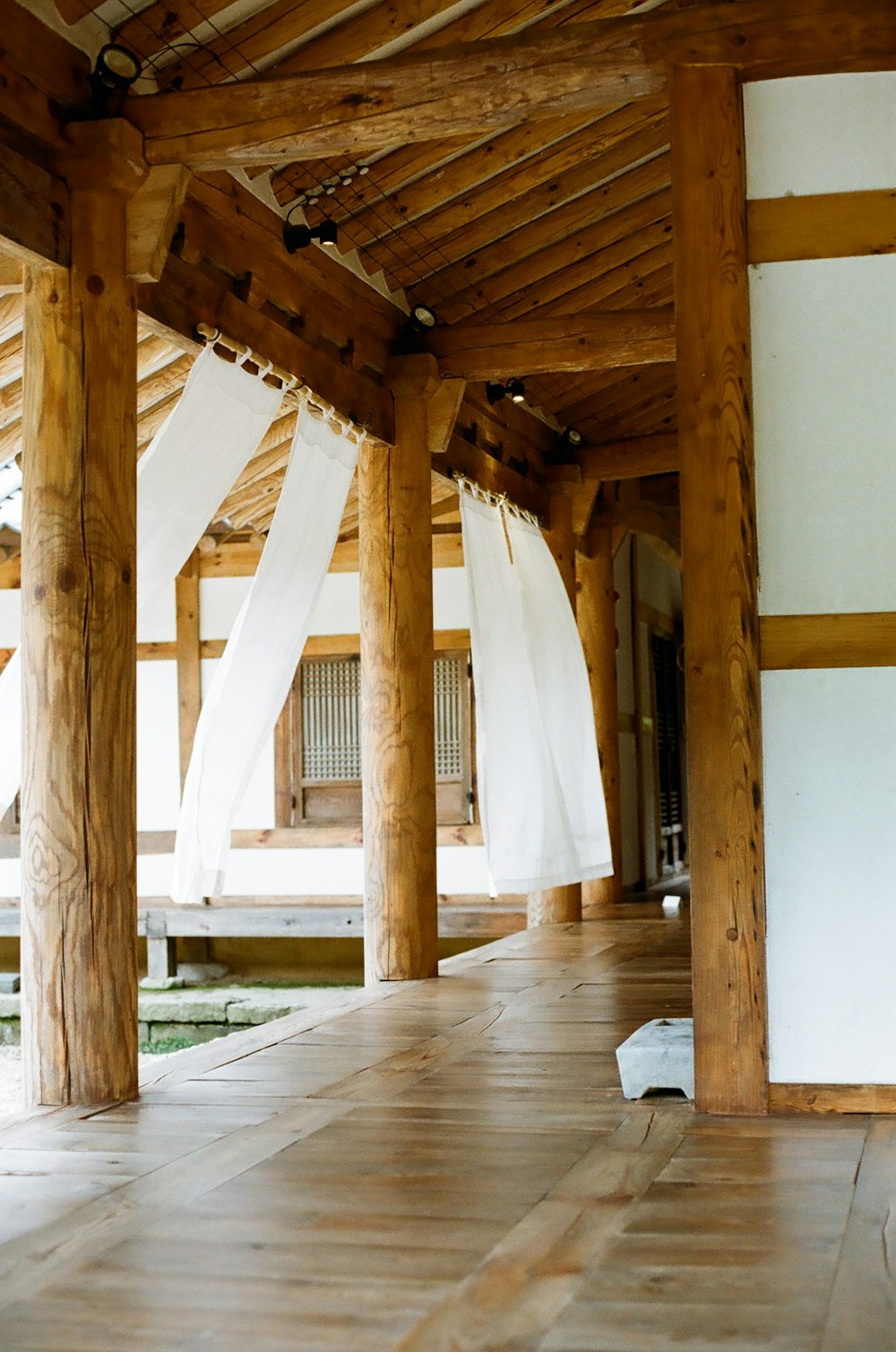 a room with wooden floors and white curtains