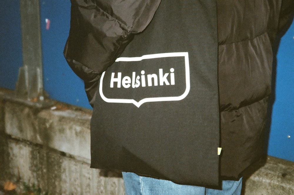 a person wearing a black jacket with a white logo on it