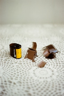 A textured photo of a film roll unspooling on a vintage table, bathed in soft light.