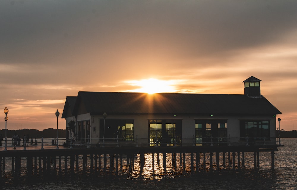 the sun is setting over a building on the water