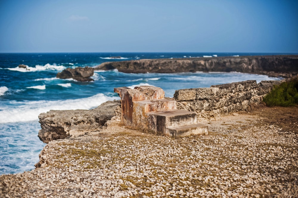 a bench sitting on top of a rocky cliff next to the ocean