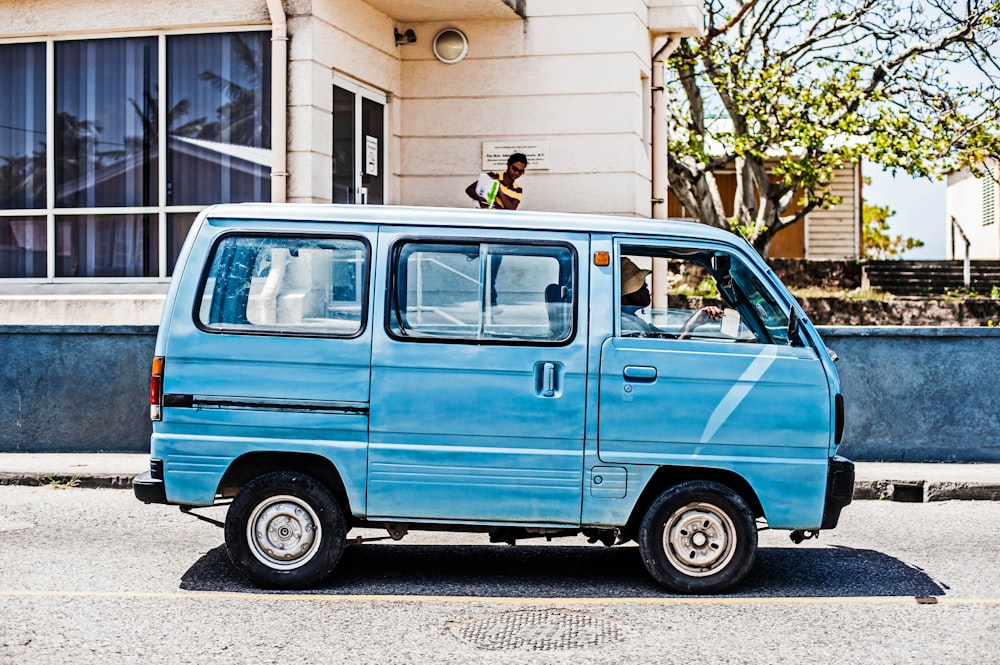 a small blue van parked in front of a building