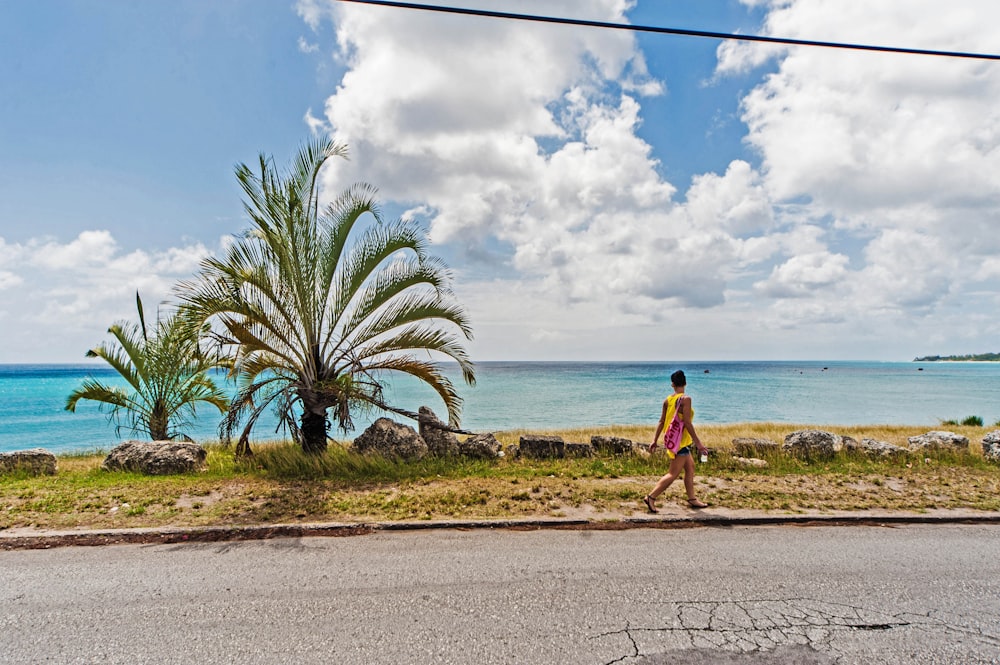 a woman walking down a street next to the ocean