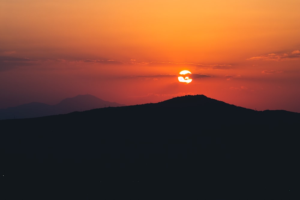 the sun is setting over a mountain range