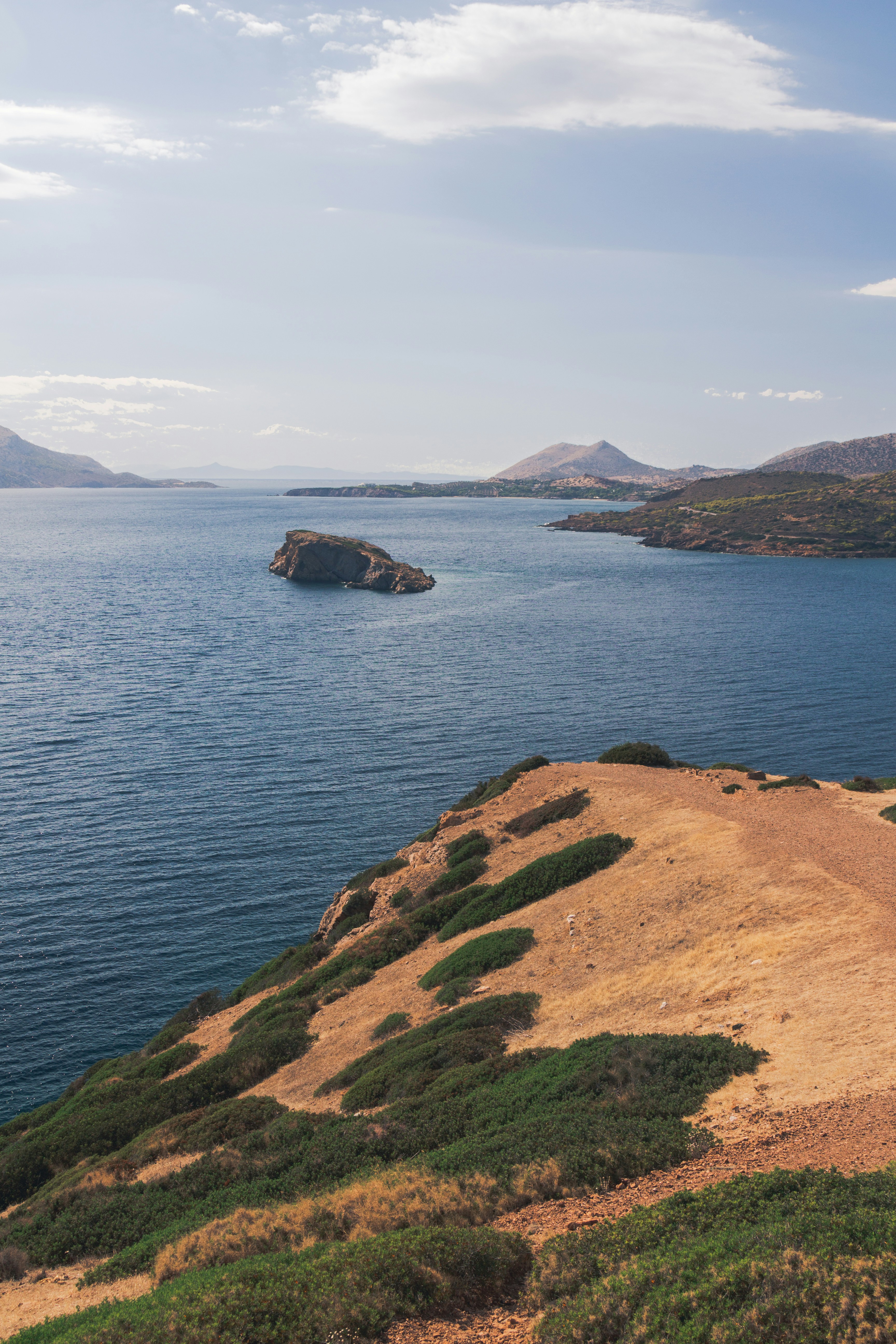 a large body of water sitting next to a lush green hillside