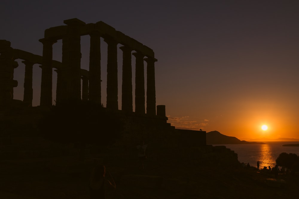 the sun is setting behind the ruins of a temple