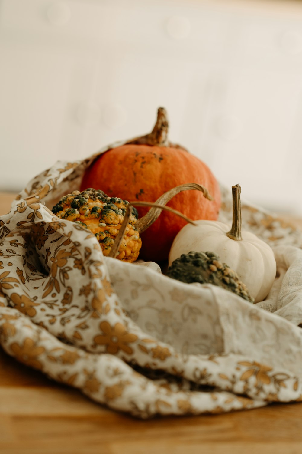 a basket filled with pumpkins and gourds on top of a wooden table