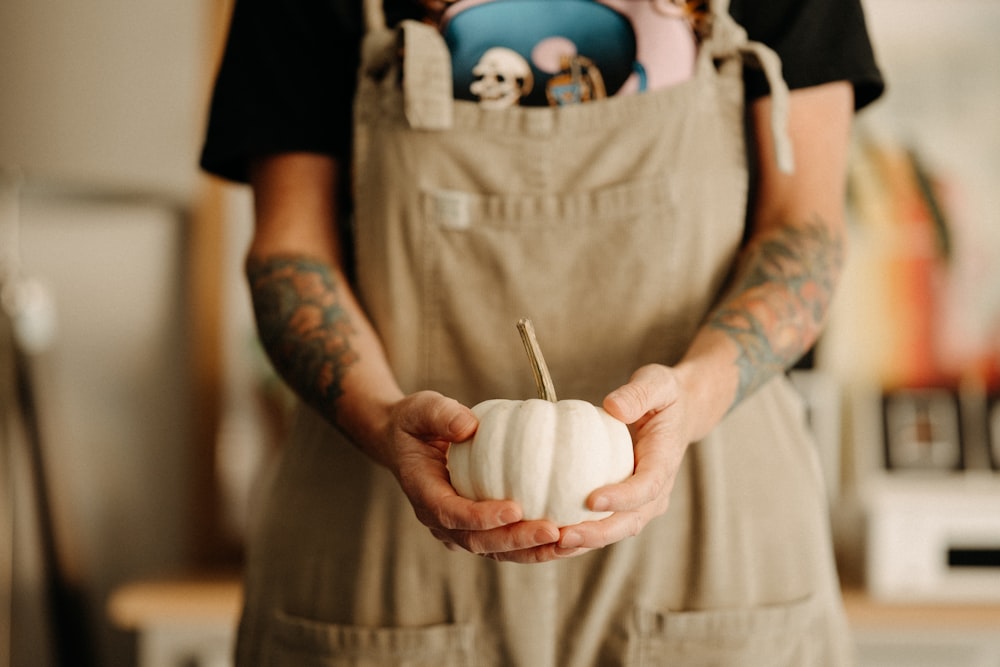 a person holding a white pumpkin in their hands