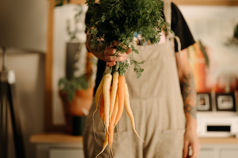 a person holding a bunch of carrots in their hands