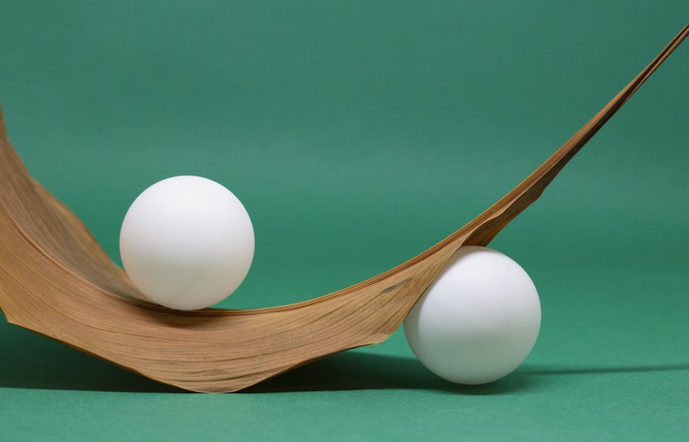 two white eggs sitting on top of a wooden stand